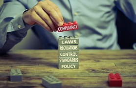 Man stacking blocks, including one saying compliance.