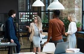 pregnant employee meeting with group of employees in office space